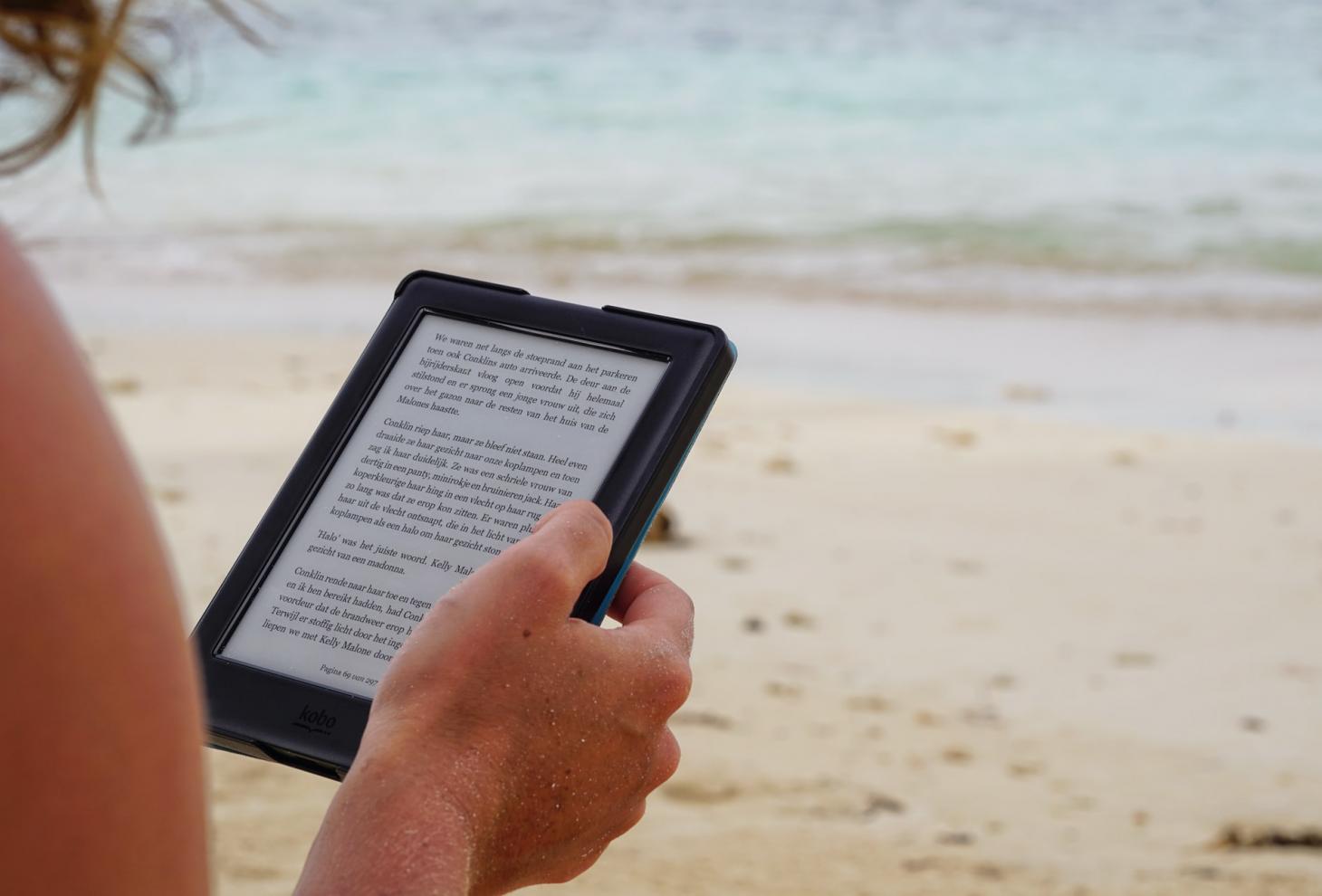 Una persona legge un libro in formato digitale sulla spiaggia